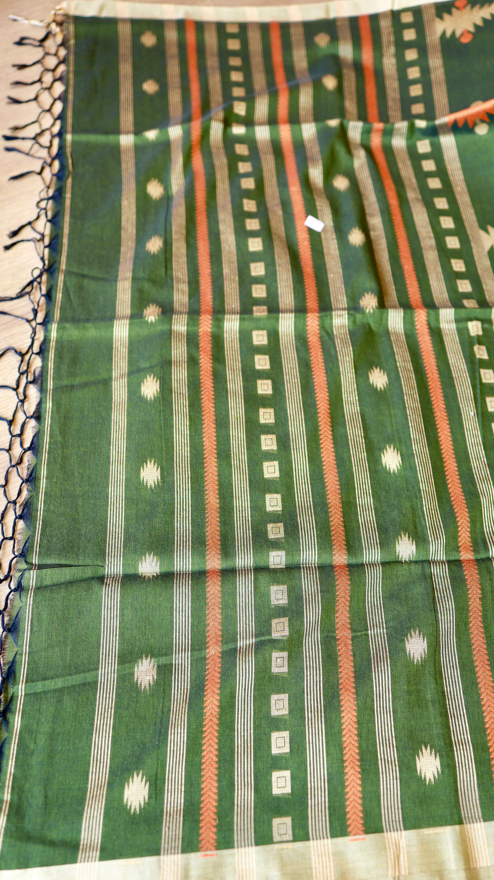 Detailed close-up of the woven pallu on a forest green khadi cotton saree showcasing striped borders and dark blue edge tassels.
