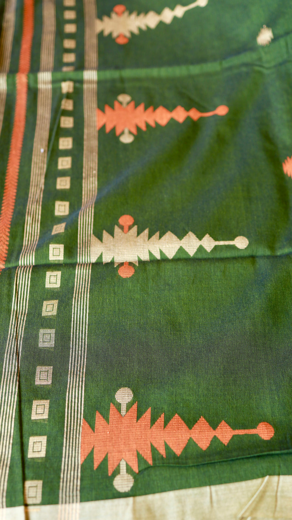 Macro close-up of the artisanal rust orange and off-white temple (mandir) motif woven on deep green khadi fabric.
