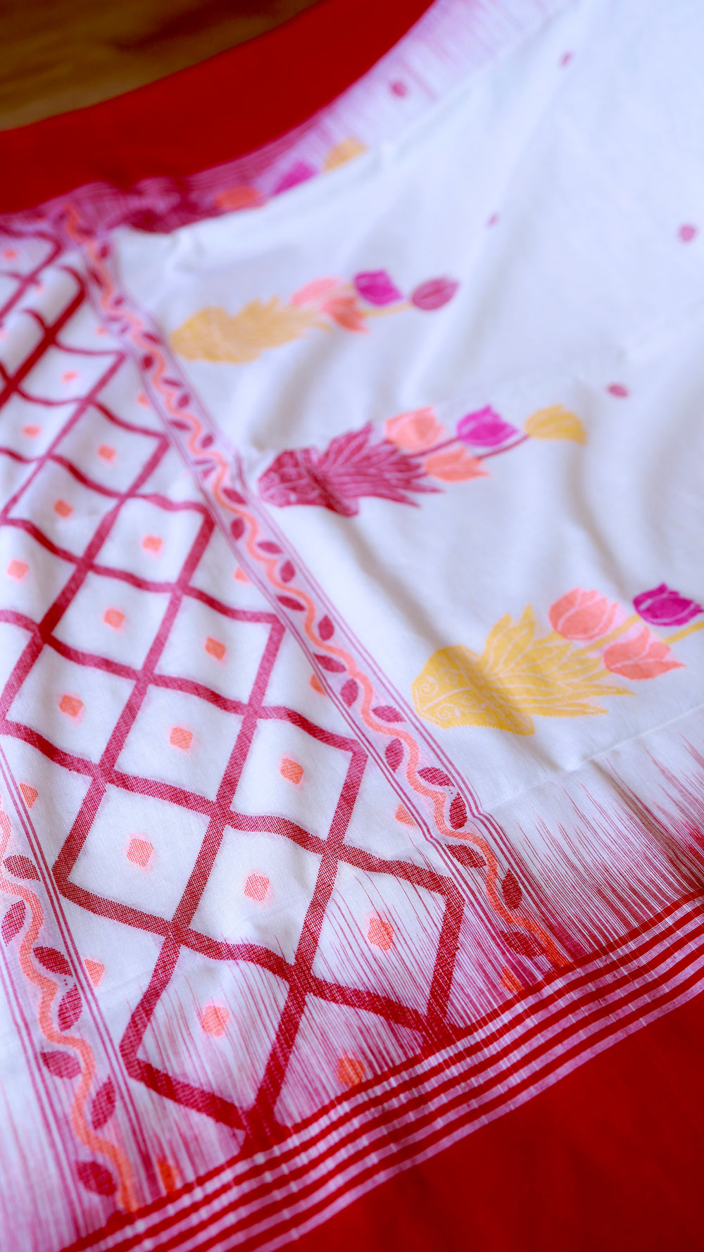 Detailed shot of the intricate red geometric lattice jaal and leaf border weave on the handwoven off-white khadi saree.