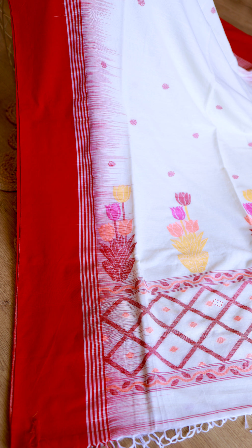 Close-up view of pristine off-white handwoven khadi cotton saree featuring crimson temples, woven geometric grid pallu, and colorful tulip motifs.
