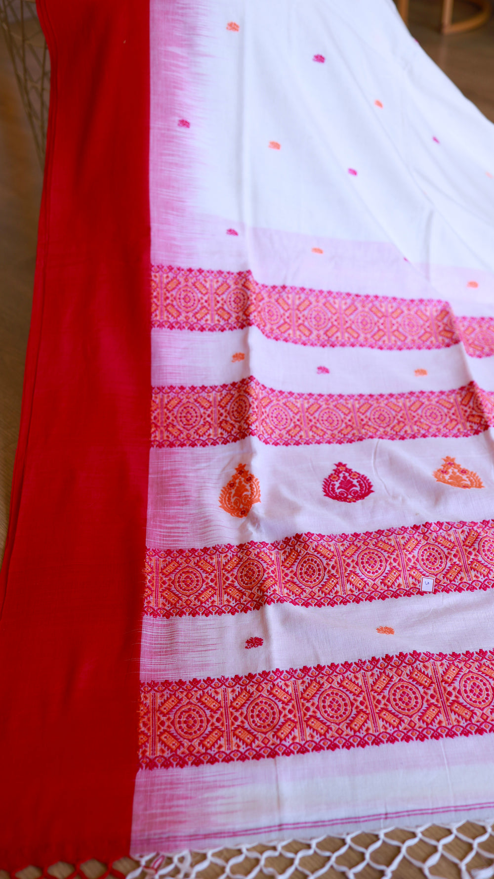 Vertical perspective emphasizing the geometric border pattern and fine horizontal lines within the white weave, leading to a vibrant red solid border.