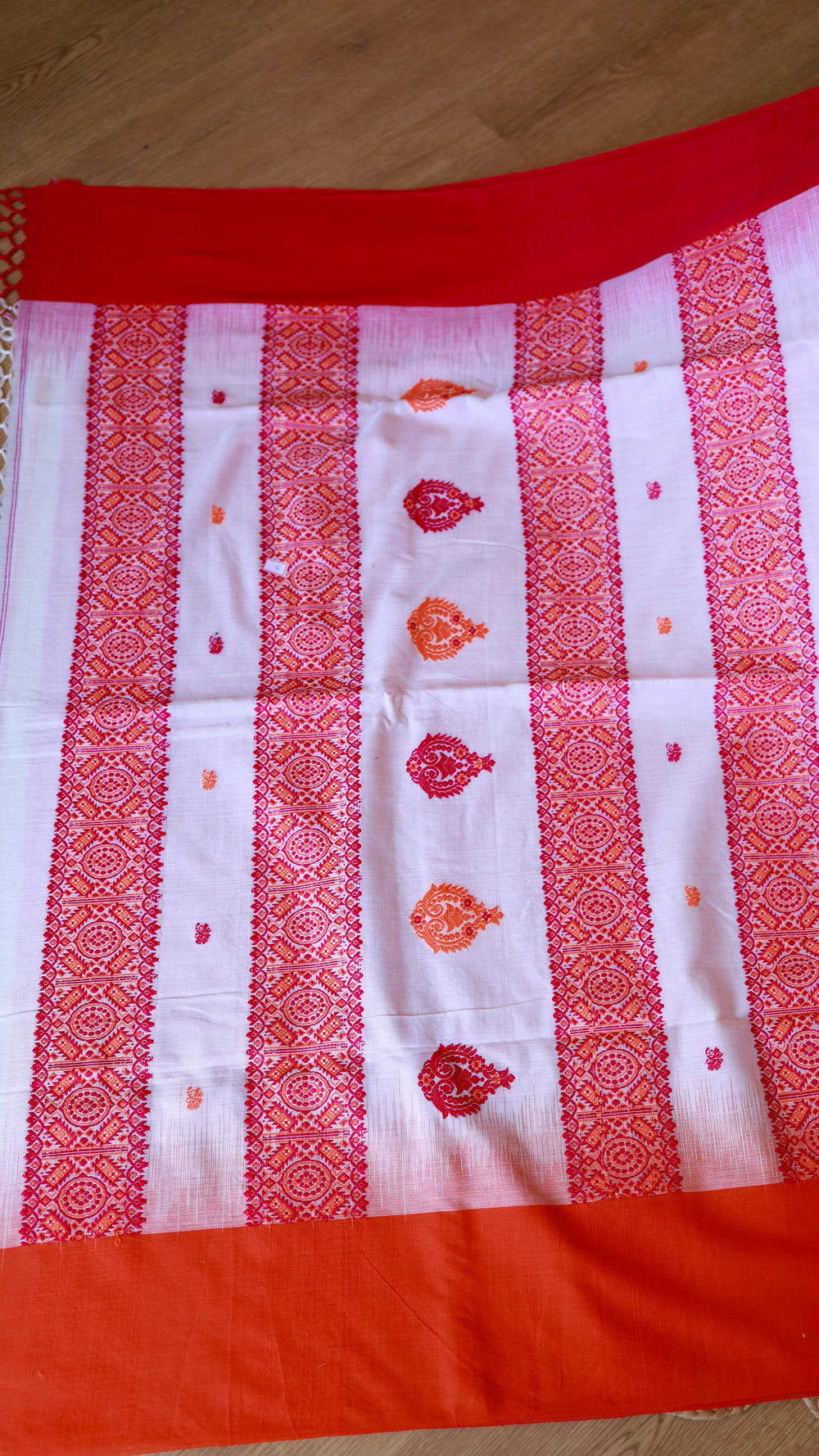 Flat lay overview showing the full width of the white Khadi Cotton Saree with distinct red geometric borders and matching red blouse piece material at the top.