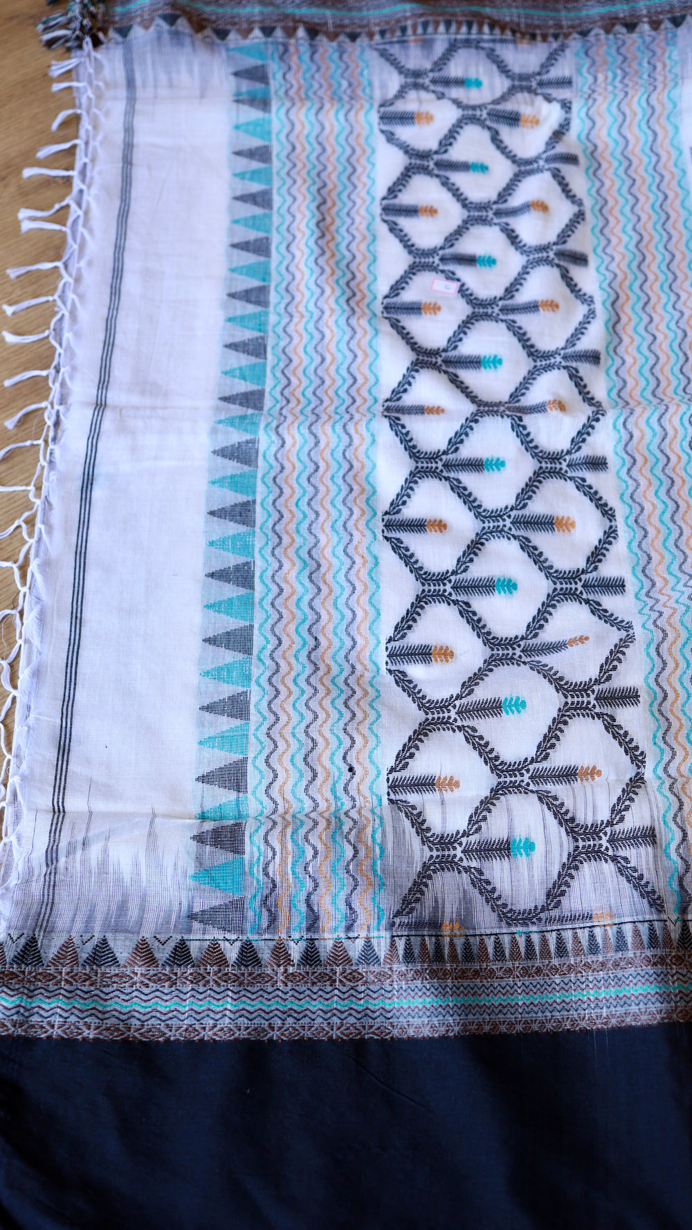 Flat-lay image highlighting the detailed woven pallu pattern, temple motifs, and white tassels of the Khadi cotton saree.