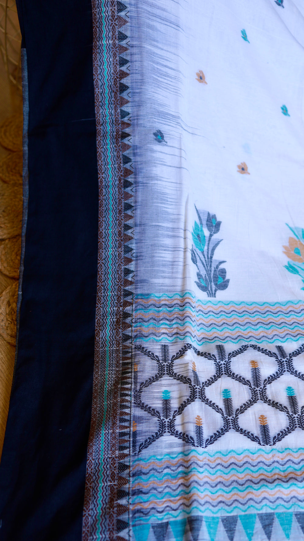 Side view of off-white Khadi saree featuring solid black border alongside turquoise wave-pattern piping.