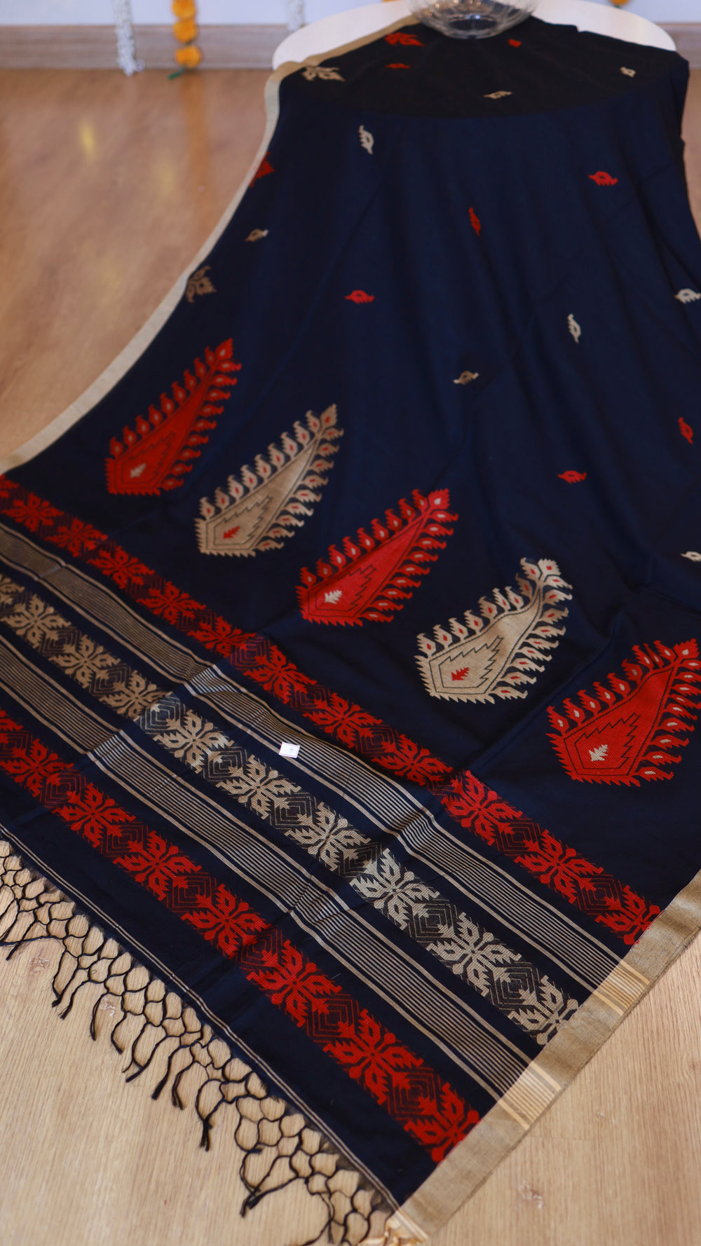 Full length view of midnight black handwoven khadi cotton saree with crimson and beige paisley pallu motifs and hand-tied tassels.