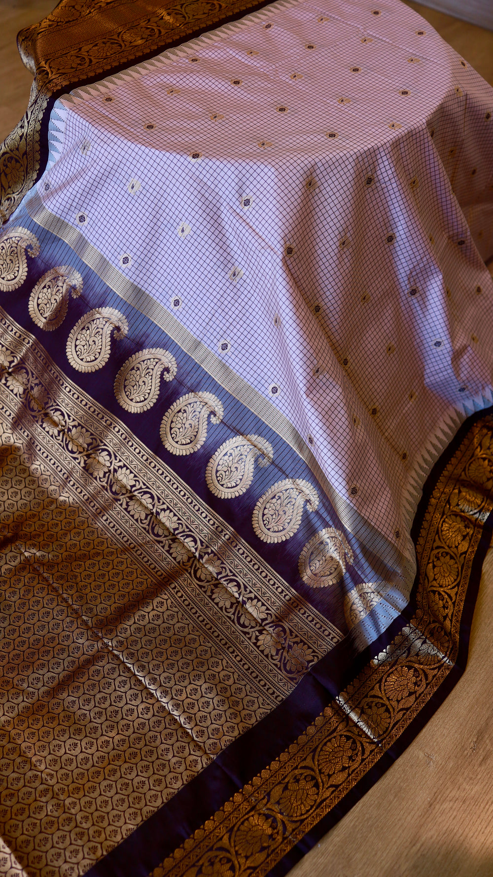 Overhead full view highlighting the contrast between the light pastel checked body and the golden zari pallu of the semi Gadwal silk saree.
