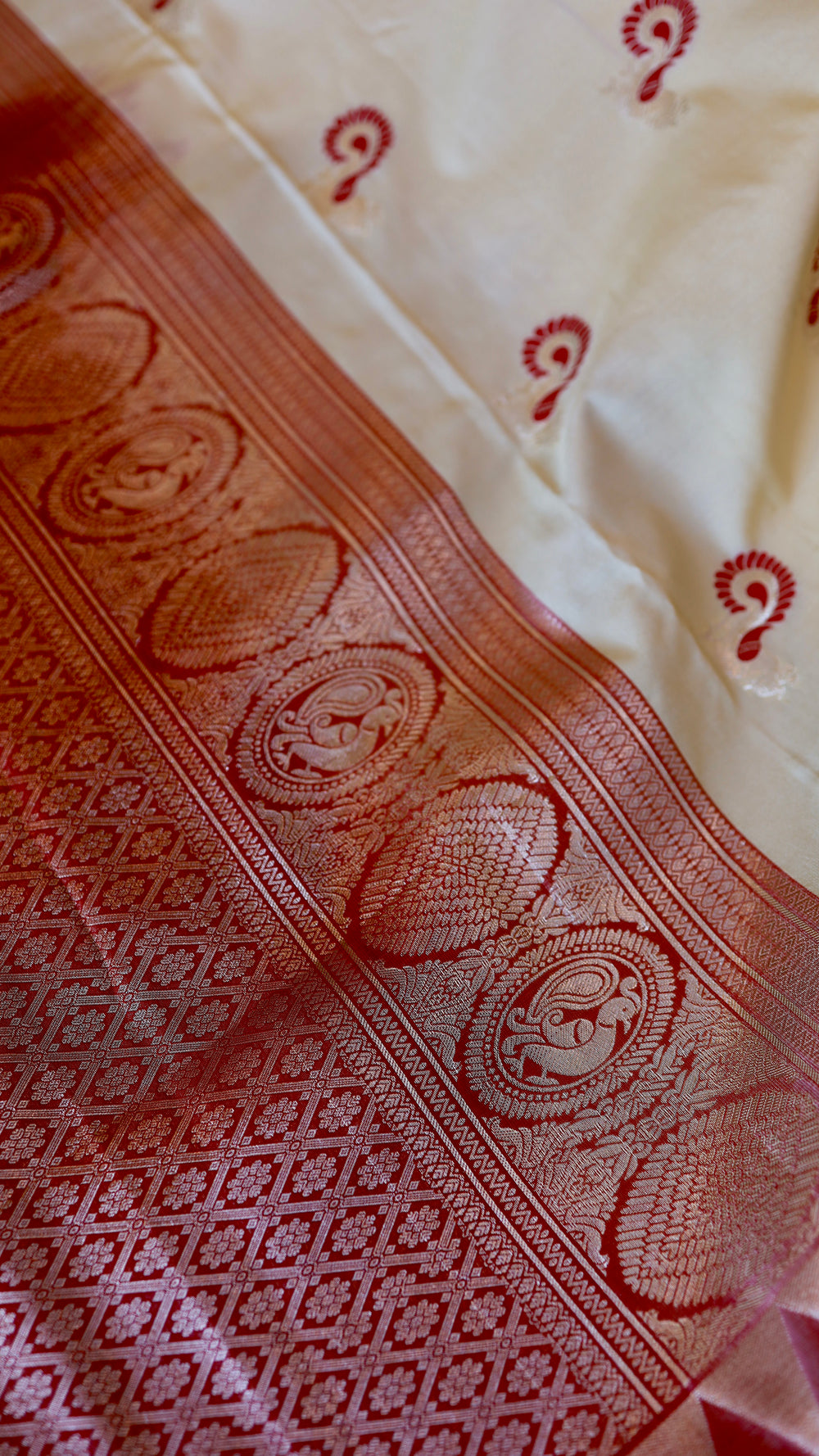 Close-up of Off White Semi Gadwal Silk Saree body showcasing detailed red paisley buttis and woven zari inner border.