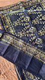 Close-up of Midnight Black Kardana Jamdani Saree showing unstitched blouse piece folded beside detailed floral and geometric pallu border with olive gold threadwork.