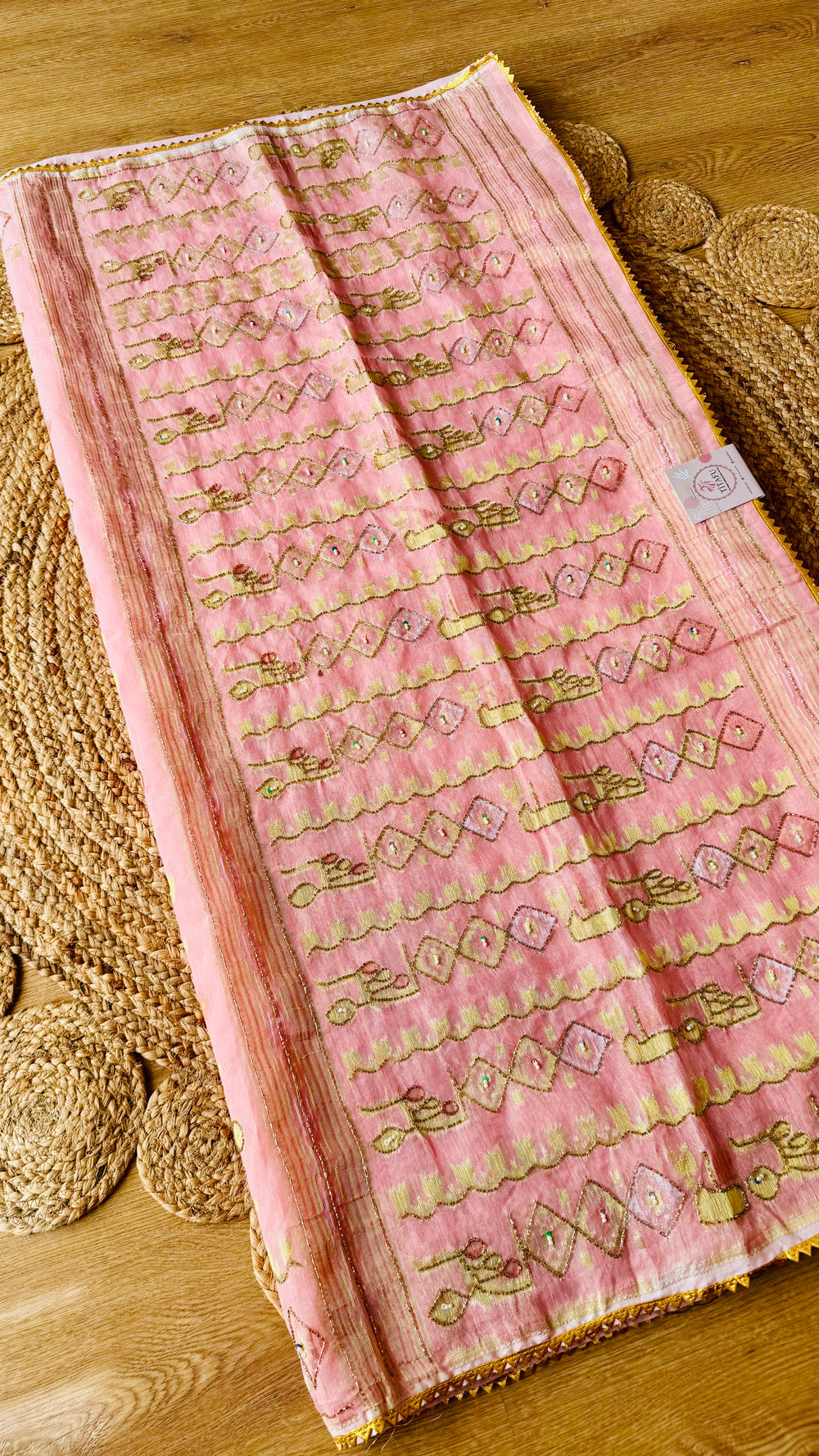 Full view of blush pink handwoven kardana jamdani saree laid flat showing gold zari pallu embellishments and lace edging.