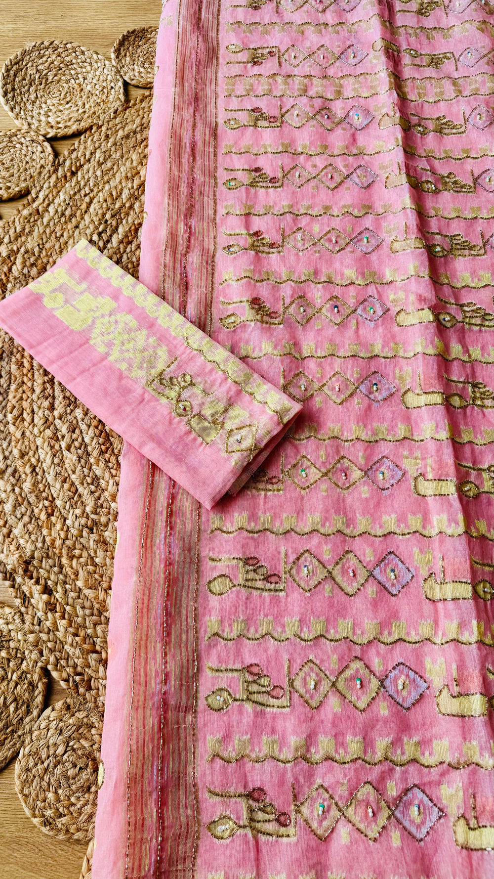 Fully opened pallu of pink kardana jamdani saree displaying intricate geometric diamond embroidery alongside matching embroidered blouse fabric.
