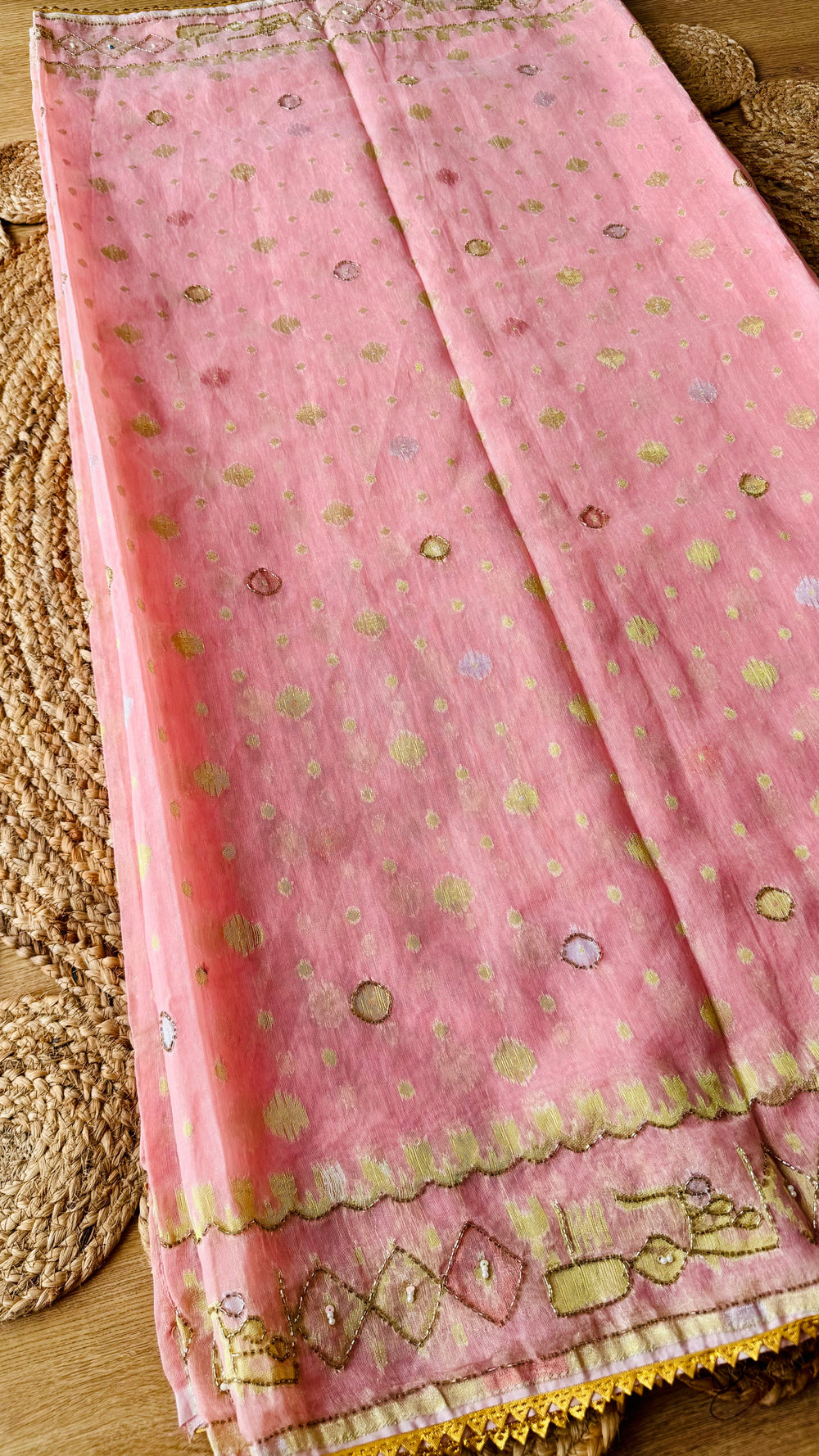 Close-up of blush pink kardana jamdani saree fabric featuring gold zari circular motifs and hand-embroidered scalloped border with cut-pipe beadwork.