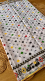 Close-up of off-white Jamdani saree pleats showing scattered colorful polka dots and an embroidered wavy Kardana border.