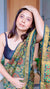 Reel video of Woman draped in a teal Maheshwari Silk Saree with red and green Ajrakh block prints, posing near a wooden door.