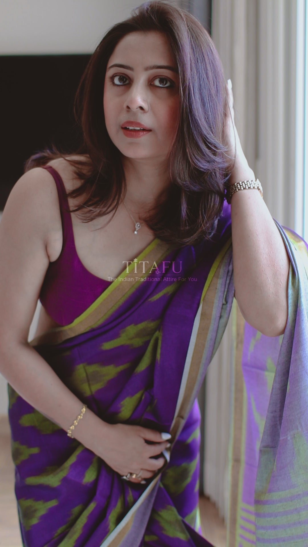 Model wearing a Royal Purple Maheswari Cotton Saree with olive green geometric ikat patterns and a gold-toned border, featuring delicate tassel work on the pallu.